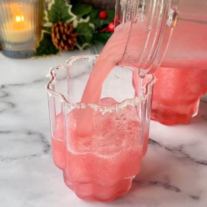 Cranberry Margarita being poured into a sugar rimmed glass on a marble bench top