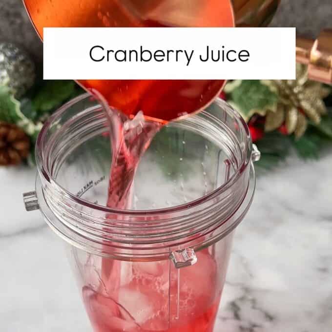 Cranberry juice being added to ice cubes in a Ninja cup.