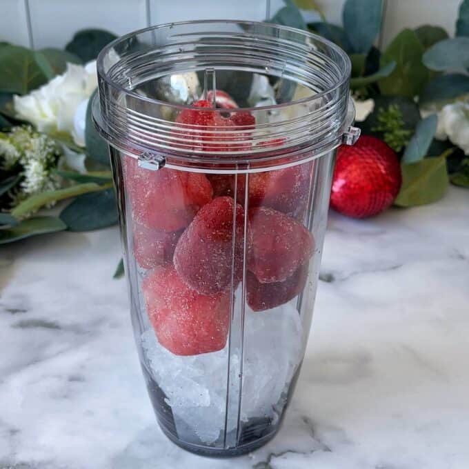 Frozen strawberries and ice cubes in a Ninja cup