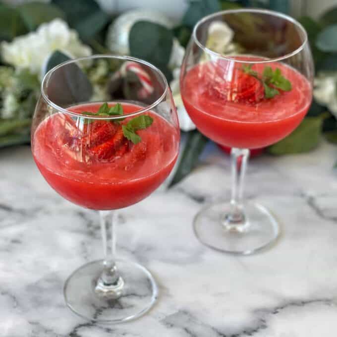 Two Strawberry Daquiri's served with a fresh strawberry in wine glasses