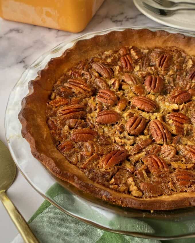 The close up of a pecan pie on a green checkered tablecloth.