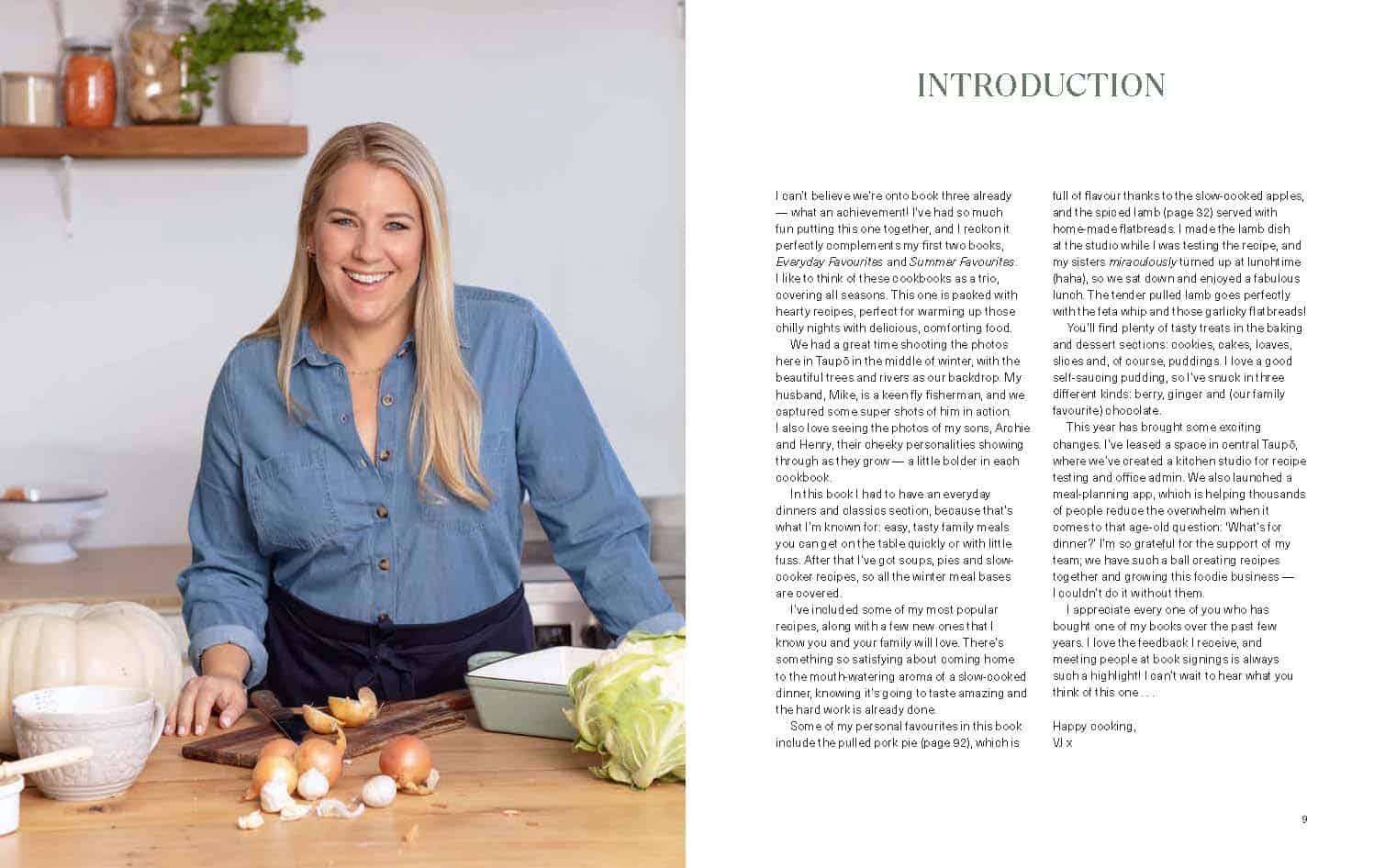 A blonde woman standing in her kitchen with a wooden bench and cooking tools in front of her. 