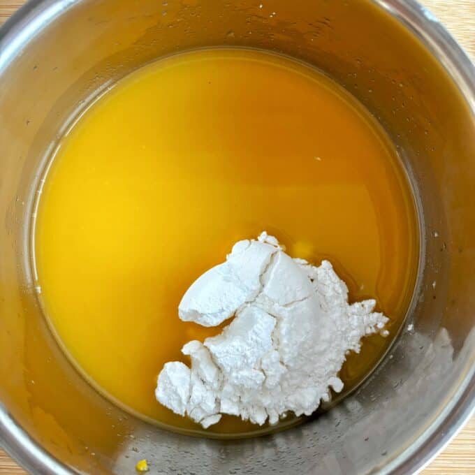 Orange juice and icing sugar in a stainless steel pot.