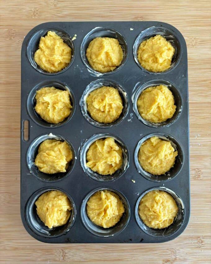 Uncooked mini jaffa cakes in a muffin tin on a wooden bench top