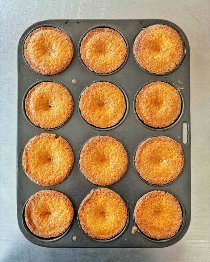 Cooked mini jaffa cakes in a muffin tin on a stainless steel bench.