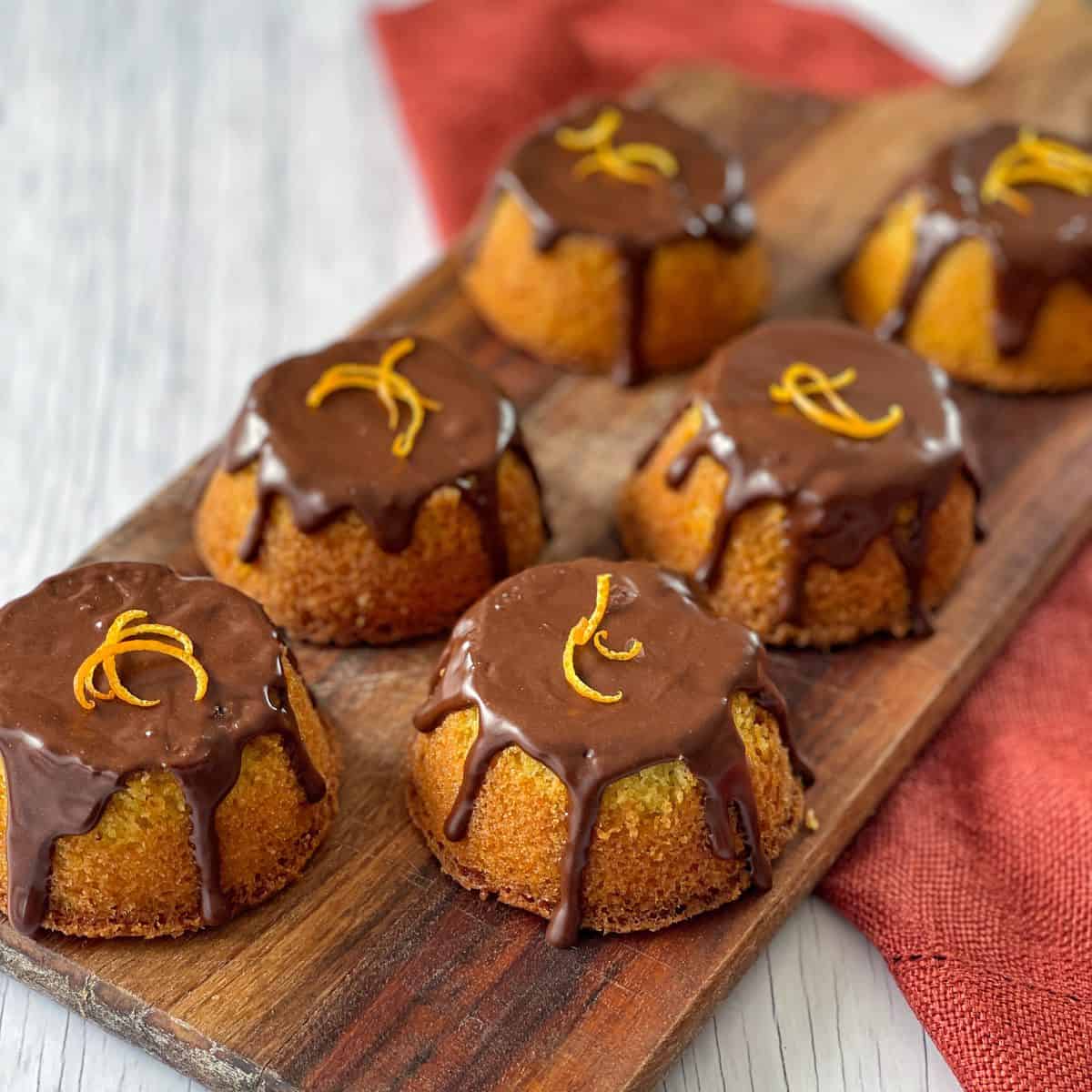 6 Mini Jaffa cakes sitting on a wooden chopping board.