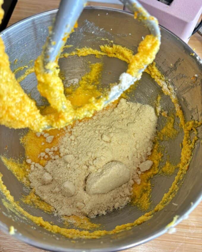 Butter egg and sugar combined  in the base of a stand mixer with almond flour on top.