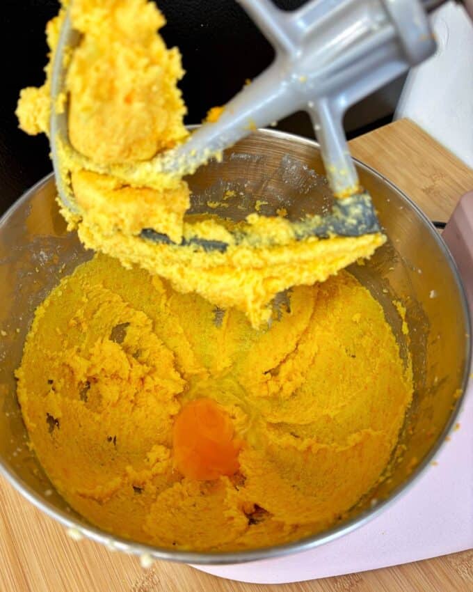 Butter egg and sugar combined  in the base of a stand mixer with an egg cracked in.