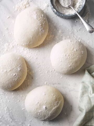 4 balls of dough on a floured bench.