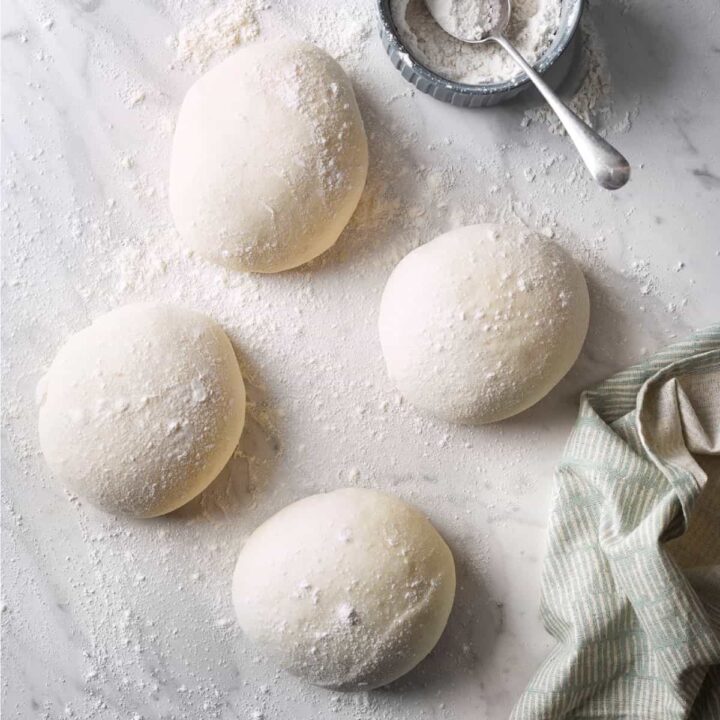 4 balls of dough on a floured bench.