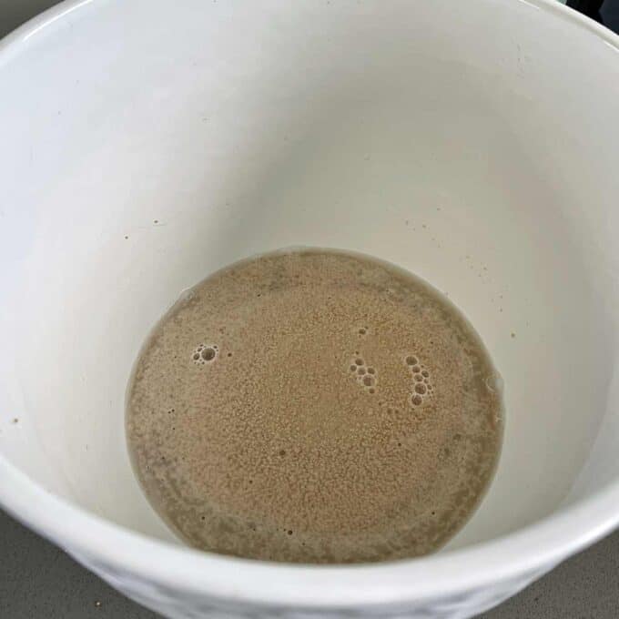 Yeast mixture foaming in a white bowl.