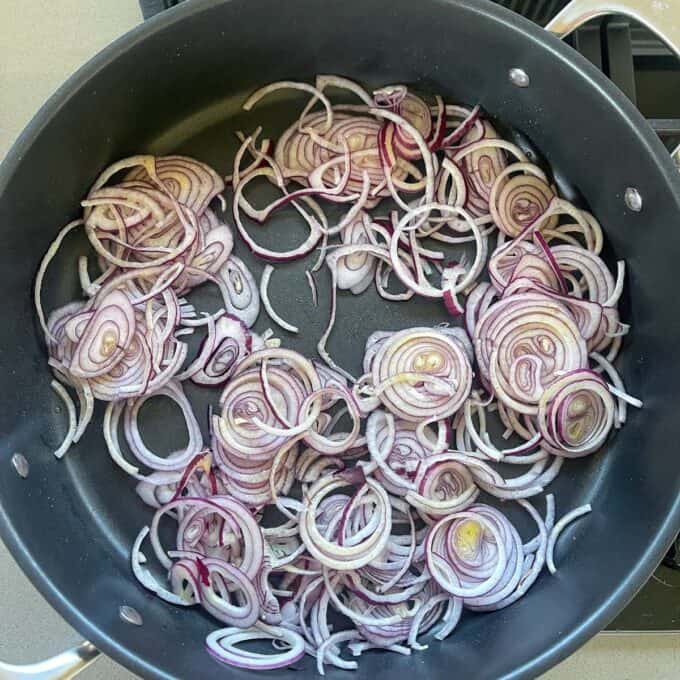 Round thin slices of red onion in a non-stick frying pan.