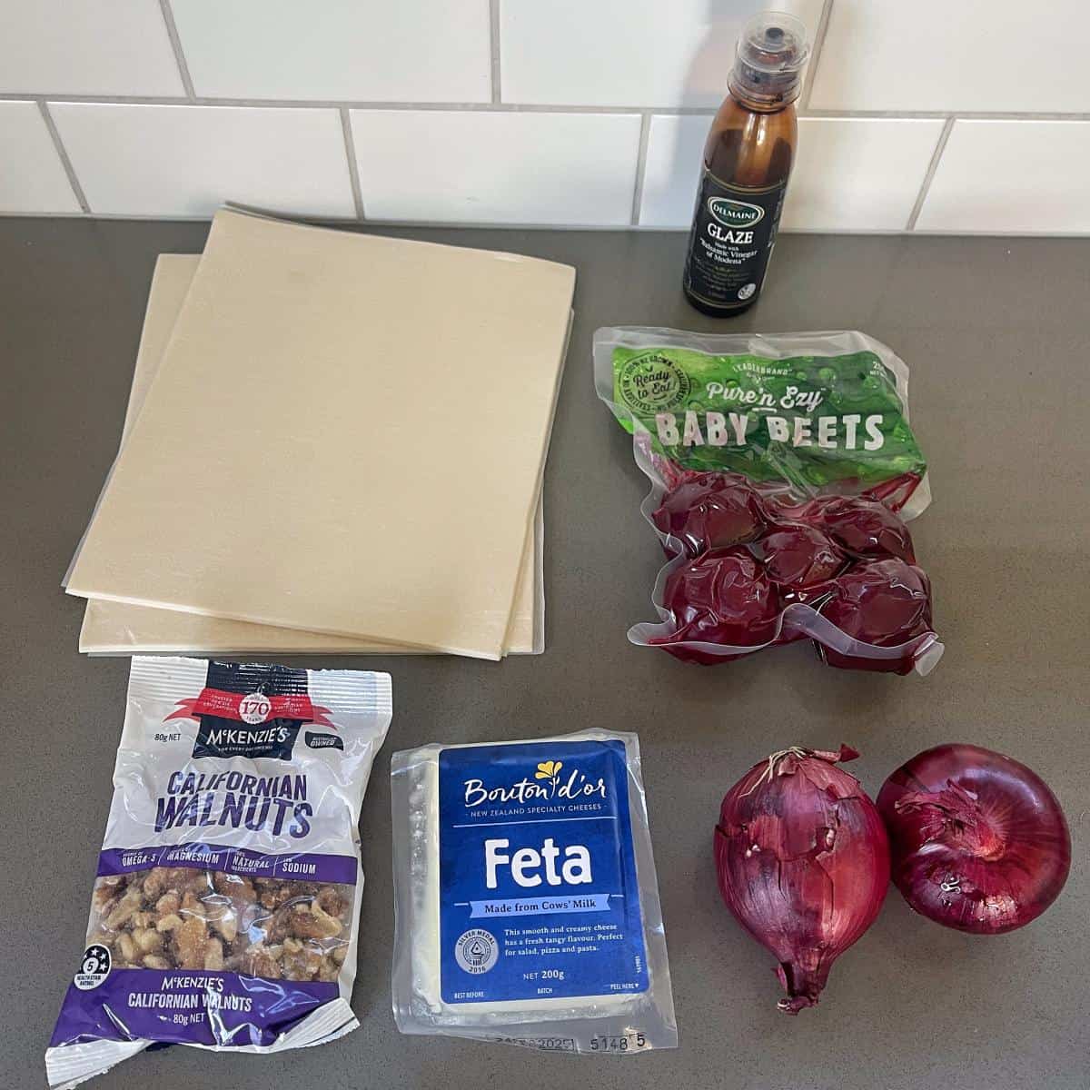 The ingredients to make a beetroot and feta tart on a grey bench top.