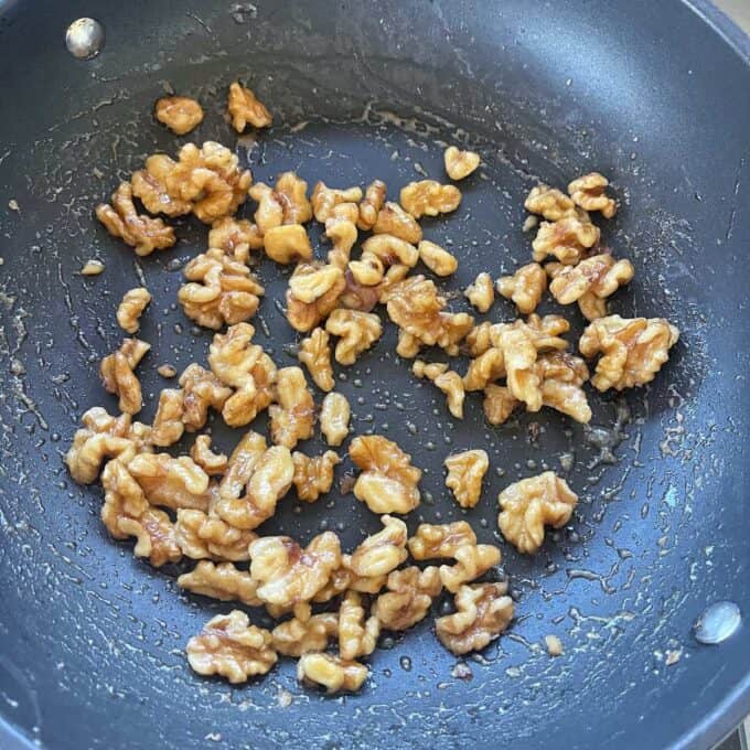 Walnuts caramelising in a non-stick frying pan.