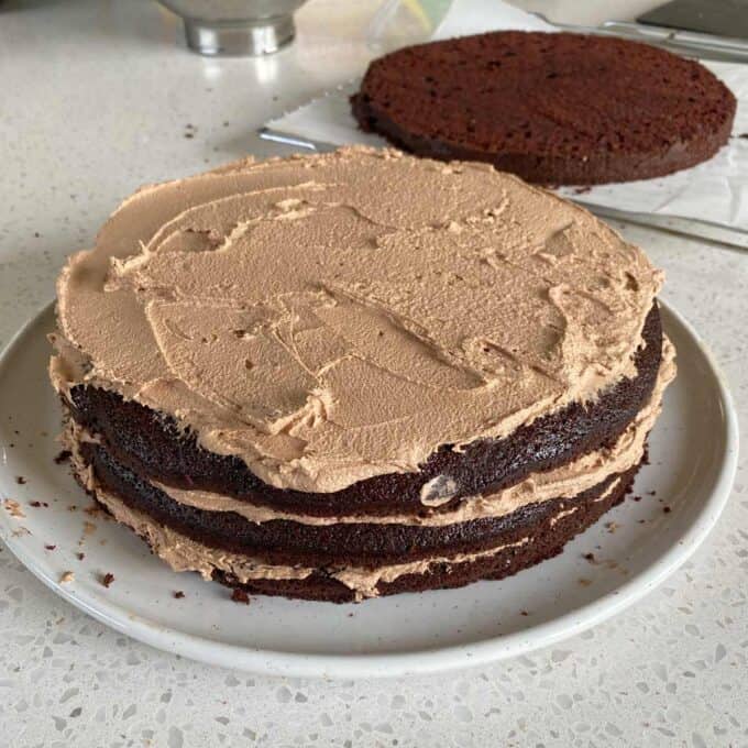 A chocolate gateaux covered in buttercream icing on white plate.