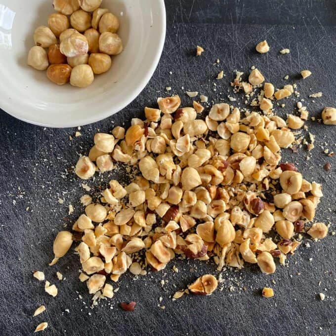 Roasted hazelnuts on a plastic chopping board.