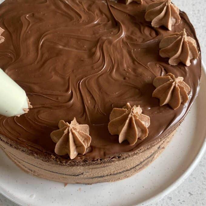 Chocolate buttercream being piped onto a Nutella gateaux.