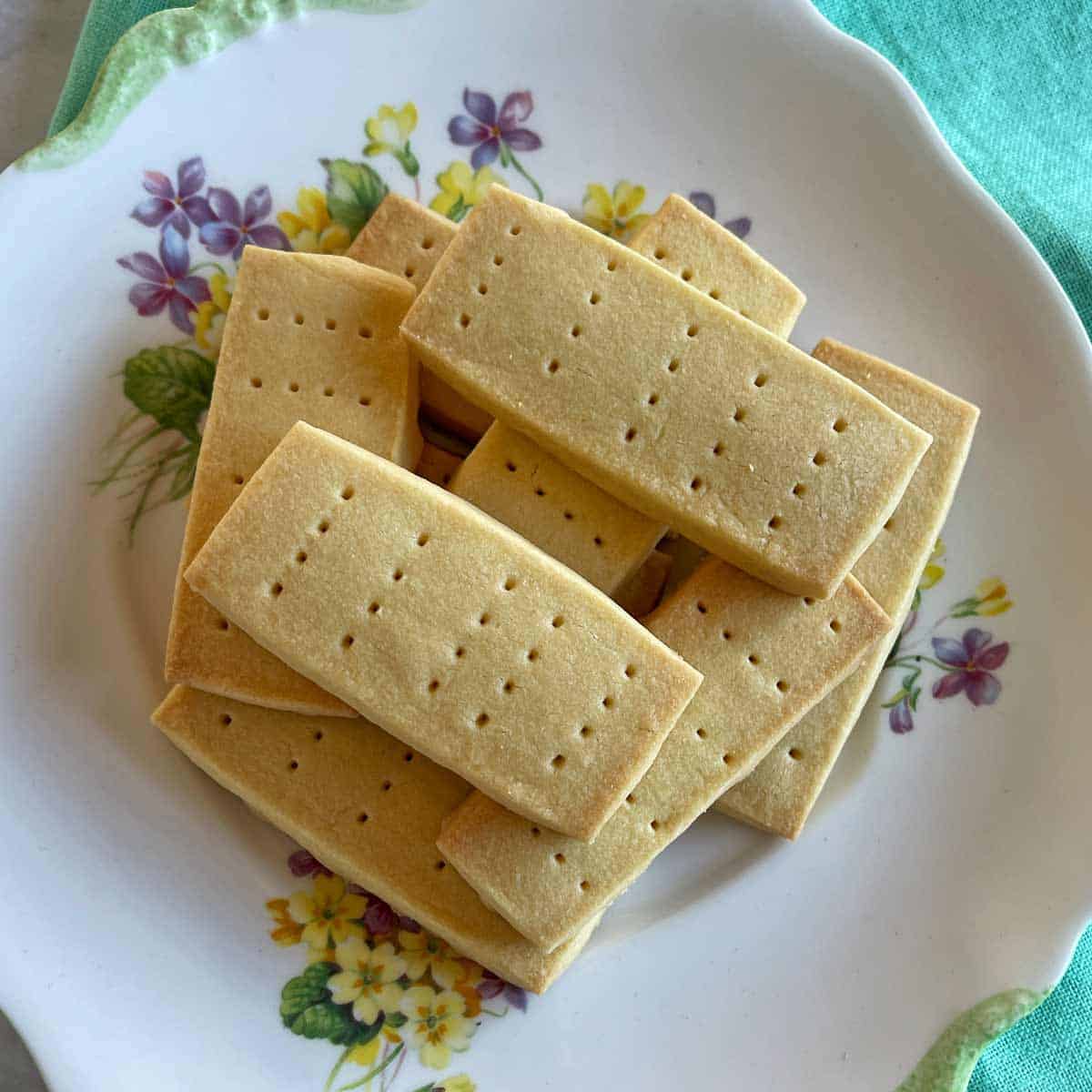 A plate of rectangular shortbread cookies with small holes, on a decorative floral-patterned dish.