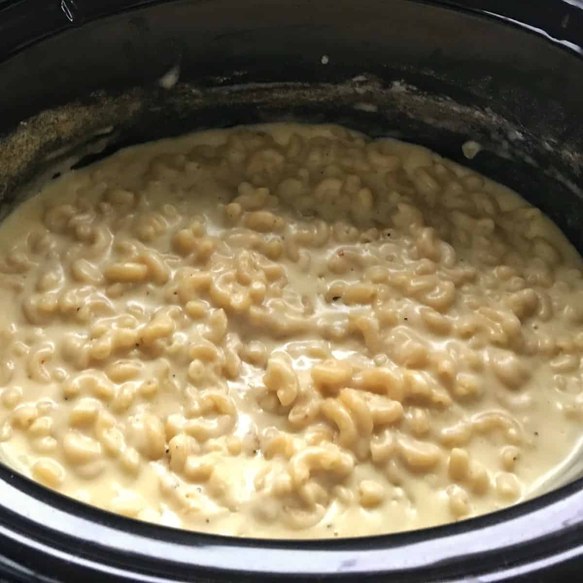 Slow Cooker Mac and Cheese Macaroni noodles in creamy cheese sauce cooking in a slow cooker.