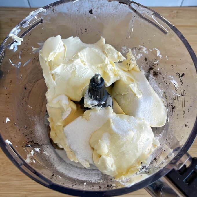 Butter and sugar are placed in a food processor bowl, ready to be mixed.