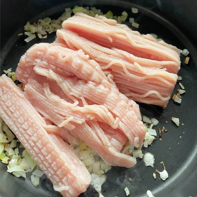 Sesame Chicken Rice Bowls Raw ground turkey placed on chopped onions in a cooking pan, ready to be cooked.