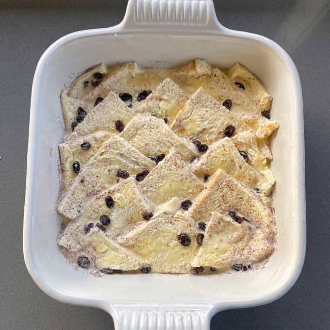 Bread and Butter Pudding A white baking dish filled with slices of bread layered with custard and sprinkled with raisins, ready for baking.
