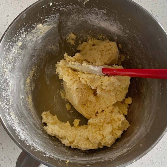 Raspberry Friands A mixing bowl with cookie dough and a red spatula on a white countertop.