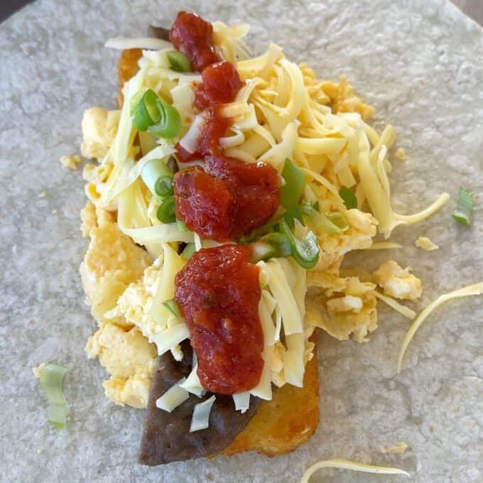 Freezer-Friendly Breakfast Burritos A flour tortilla topped with scrambled eggs, shredded cheese, black beans, green onions, and salsa.