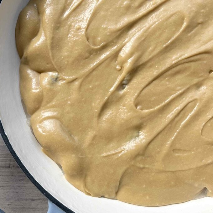 Caramel Apple Sponge Pudding Close-up of smooth, light brown batter spread evenly in a white round baking dish, ready for baking.