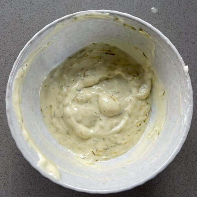 Homemade McChicken Tacos A white bowl containing a thick, creamy sauce with visible herbs, placed on a gray surface.