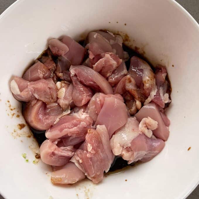 Air Fryer Karaage Chicken Raw pieces of chicken marinating in a white bowl with a dark sauce.