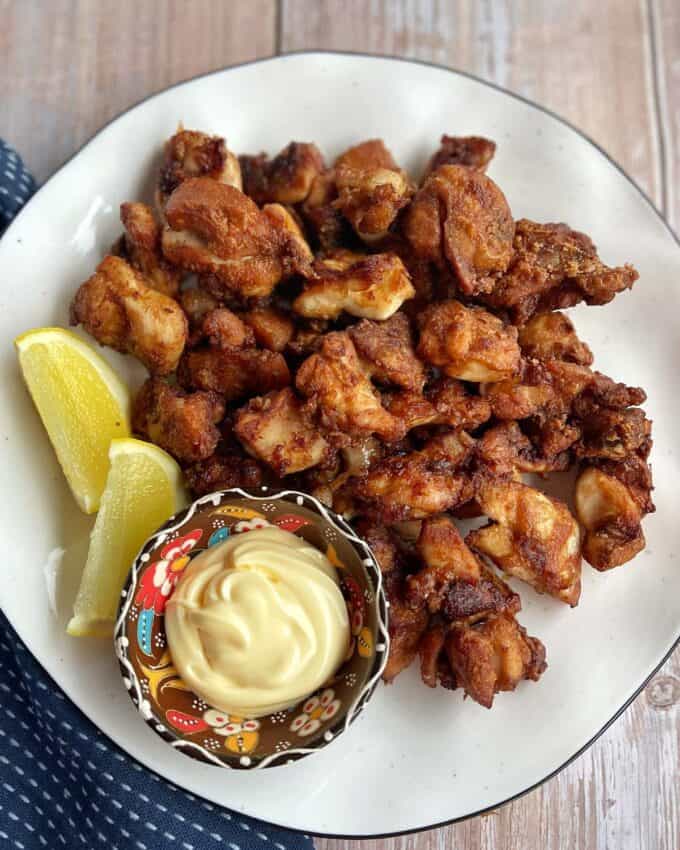 Air Fryer Karaage Chicken A plate of fried chicken pieces served with lemon wedges and a bowl of mayonnaise-based dipping sauce.