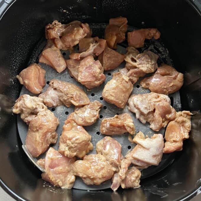 Air Fryer Karaage Chicken Raw marinated chicken pieces are arranged in a single layer inside an air fryer basket, ready to be cooked.