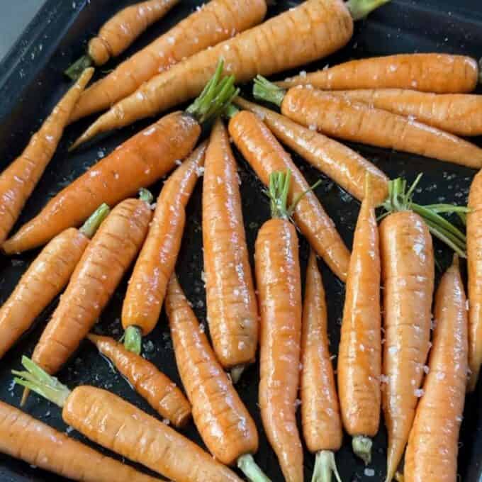 Roasted Carrot with Feta Whip A baking tray filled with whole, unpeeled carrots sprinkled with coarse salt, ready for roasting.