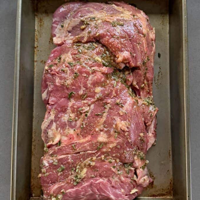 BBQ Lamb with Fresh Mint Sauce Raw marinated pork shoulder placed in a metal baking tray, ready to be cooked.