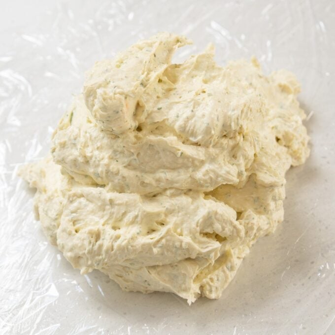 Christmas Cheeseball A mound of herbed compound butter on a sheet of plastic wrap, ready to be shaped or used.