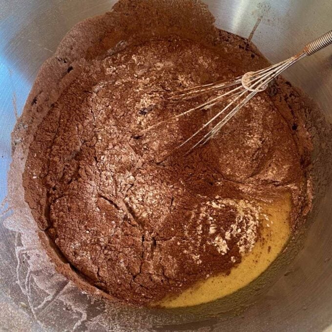Big One Bowl Chocolate Brownie A bowl containing cocoa powder, flour, and wet ingredients being mixed with a whisk, likely for baking.