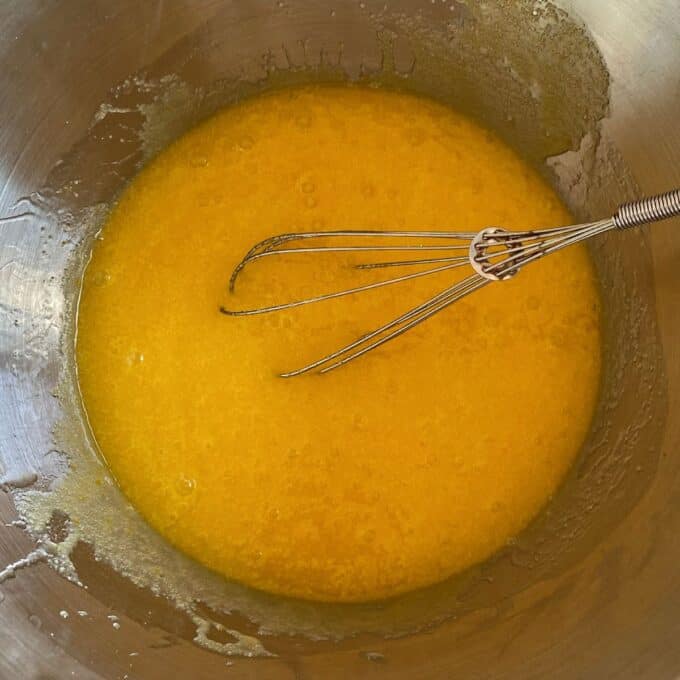 Big One Bowl Chocolate Brownie A metal whisk rests in a stainless steel bowl containing a yellow, partially mixed liquid mixture.