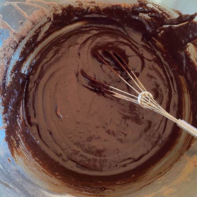 Big One Bowl Chocolate Brownie A metal whisk rests in a bowl filled with thick chocolate batter, with some batter clinging to the sides of the bowl.