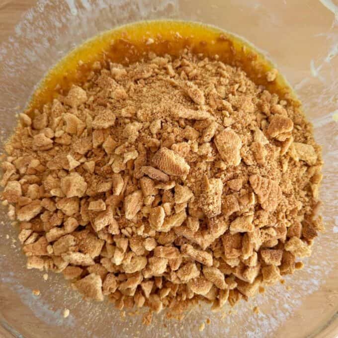 Speckled Mini Egg Slice A glass bowl containing crushed graham crackers mixed with melted butter.