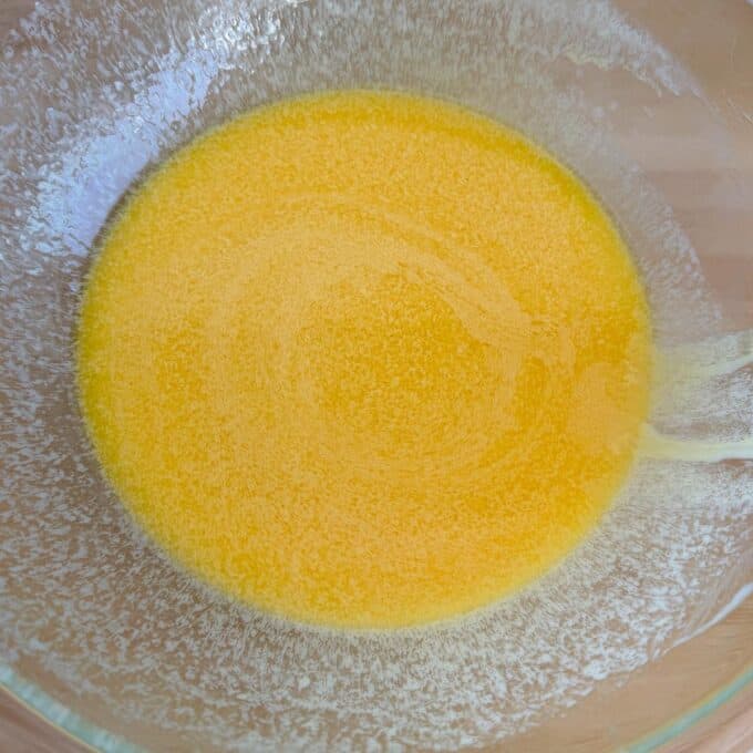 Speckled Mini Egg Slice A glass bowl containing melted yellow butter with a slightly frothy texture around the edges.