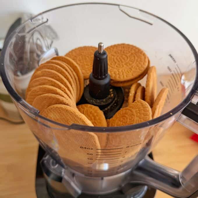 Speckled Mini Egg Slice A food processor bowl filled with round, golden-brown biscuits arranged around the central blade.