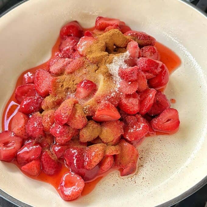 Strawberry Cobbler Sliced strawberries coated with sugar and ground cinnamon in a white pan, ready to be cooked.