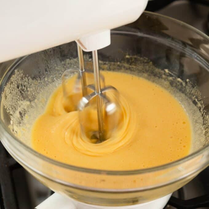 Berry Semifreddo A stand mixer is blending a yellow-orange batter in a glass mixing bowl.