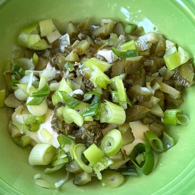 Crispy Panko Fish Bites A green bowl containing chopped green onions, diced pickles, and a creamy white dressing.