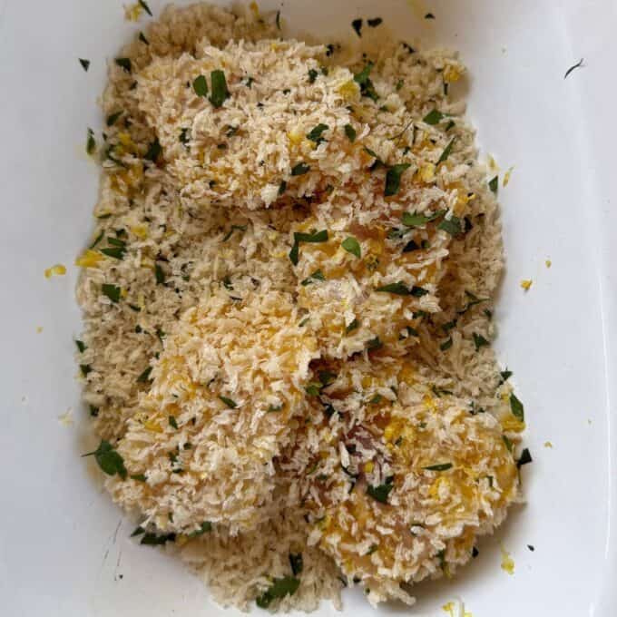 Crispy Panko Fish Bites Breaded food items, possibly cutlets or patties, coated with panko breadcrumbs and chopped herbs in a white container.