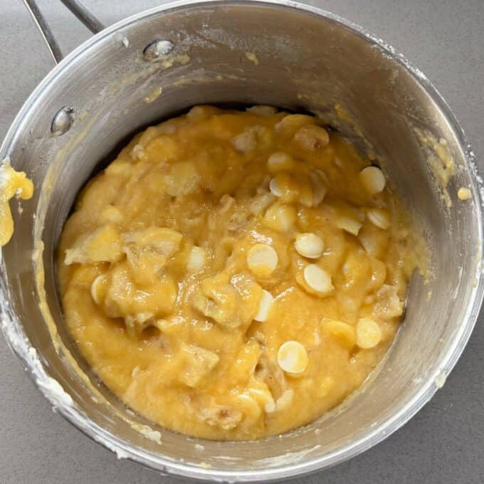 Feijoa and White Blondie Batter with white chocolate chips and banana chunks in a stainless steel mixing bowl on a gray surface.