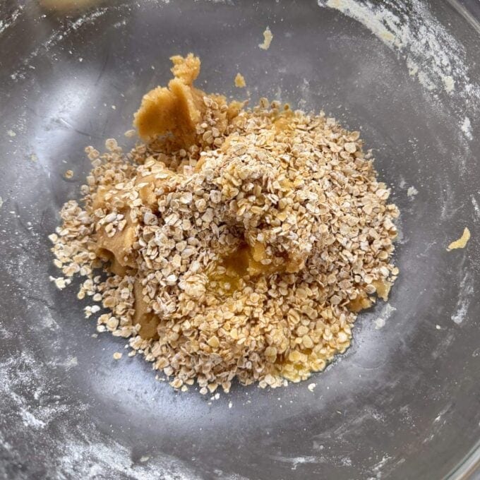 Feijoa and Apple Crumble Slice A mixing bowl containing cookie dough with oats and wet ingredients partially combined.