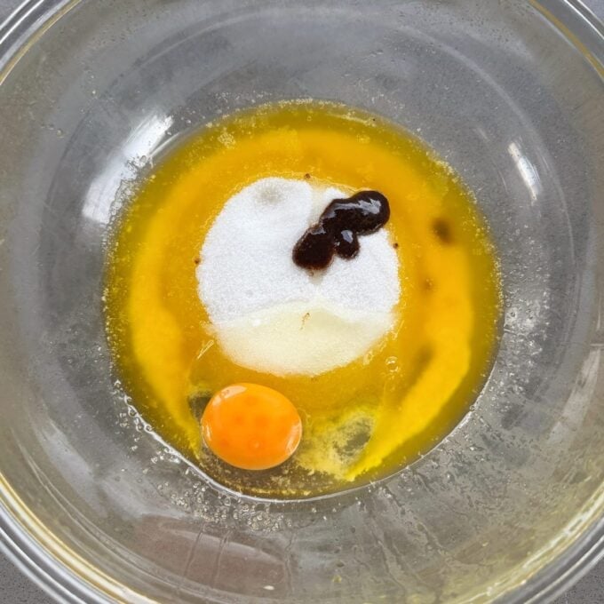 Feijoa and Apple Crumble Slice A mixing bowl containing an egg yolk, granulated sugar, melted butter, and a small amount of vanilla extract.