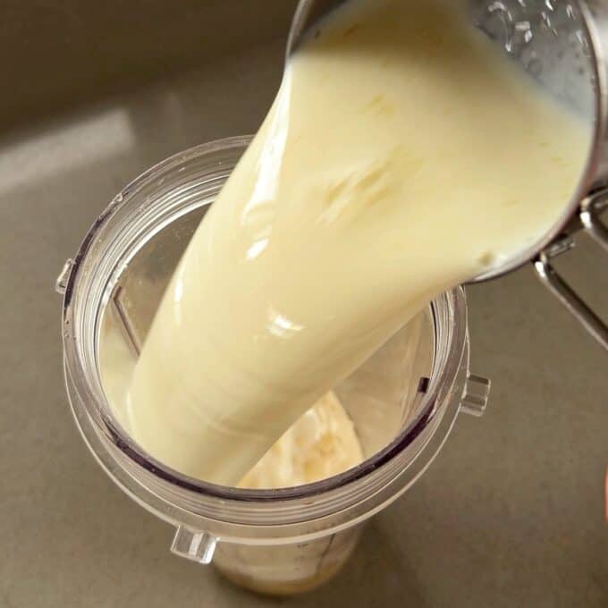 Feijoa Chia Puddings A measuring cup pours a thick, creamy liquid into a blender cup on a kitchen countertop.